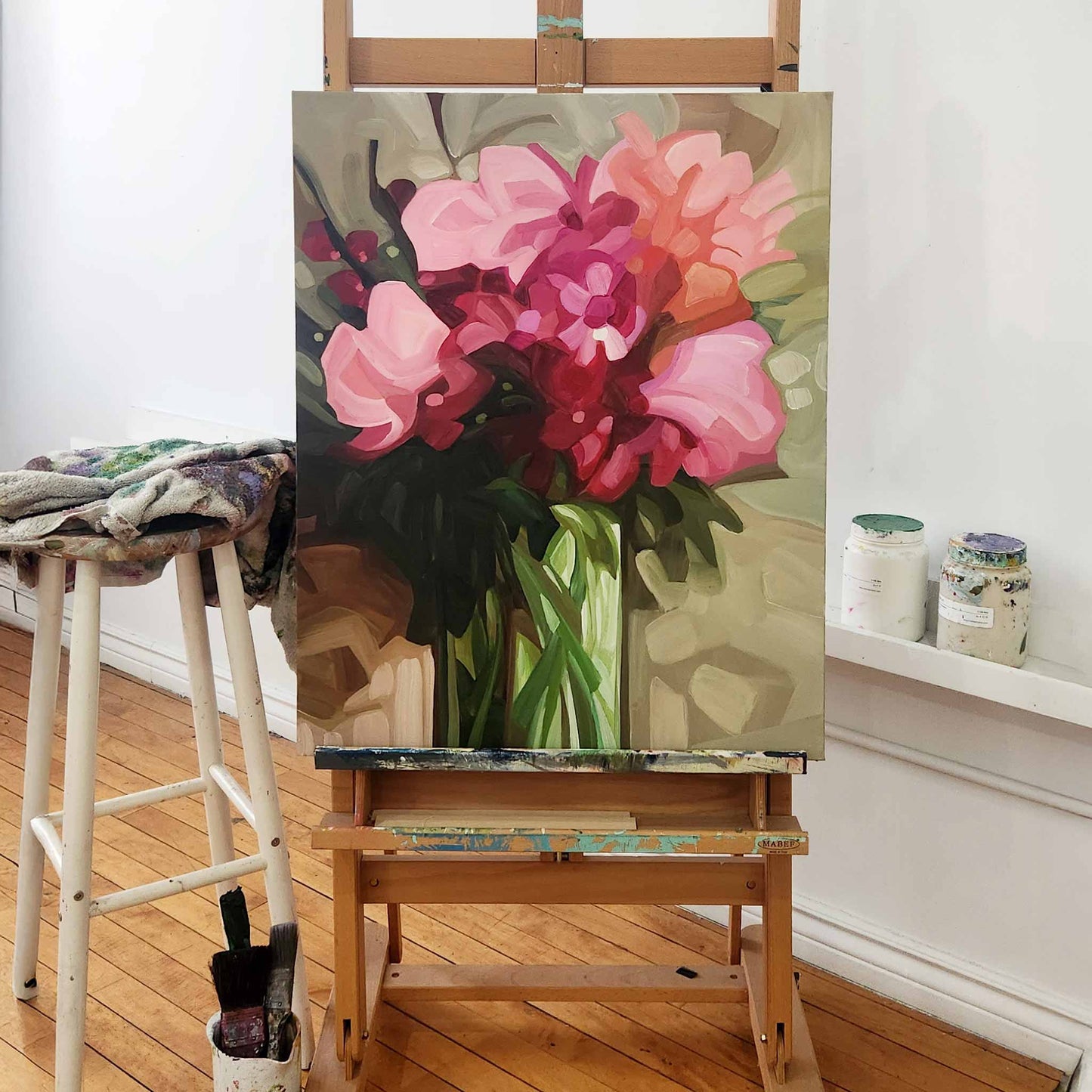 abstract flower painting with pink blooms on easel in studio