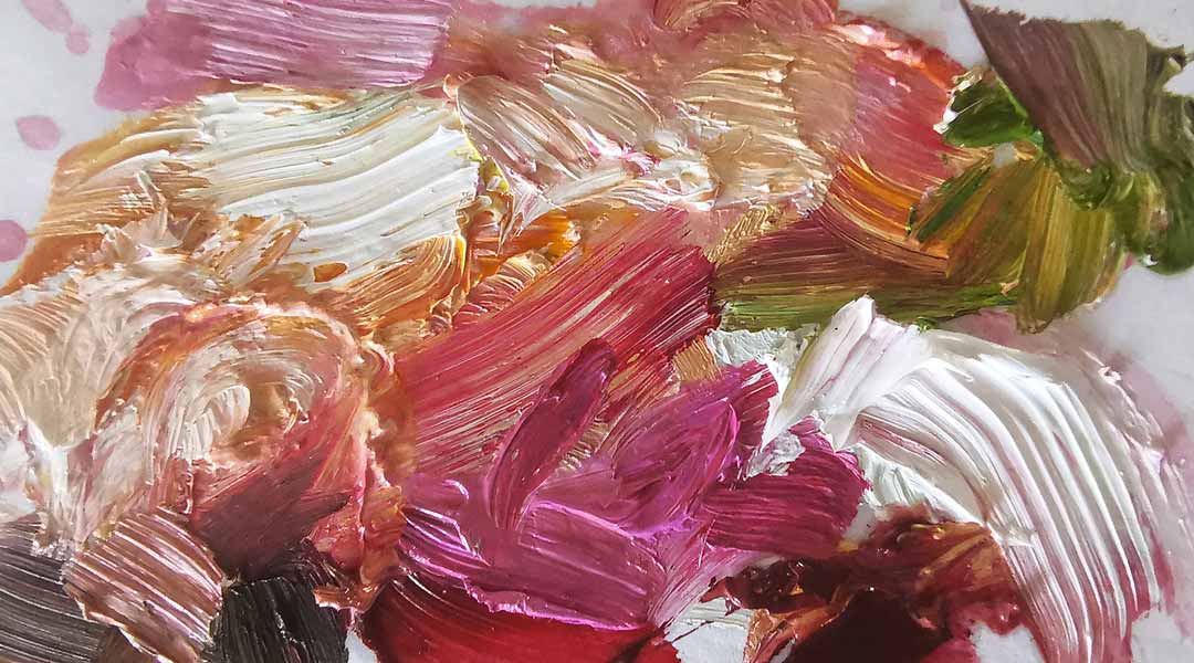 close up of brightly colored oil paints mixed on a paint palette