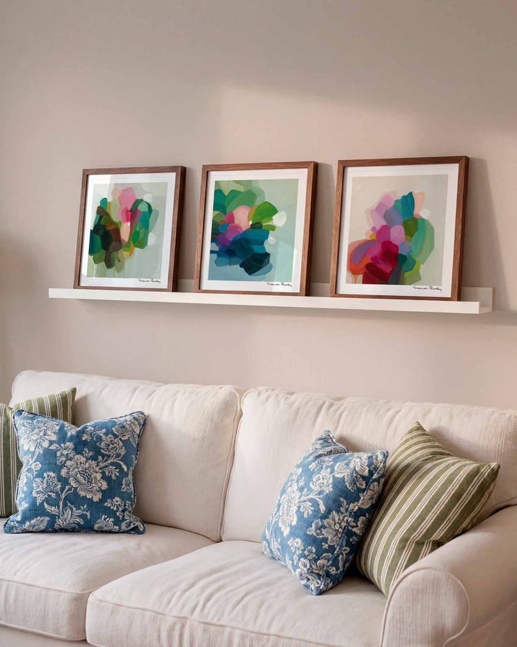 three abstract art prints over a sofa