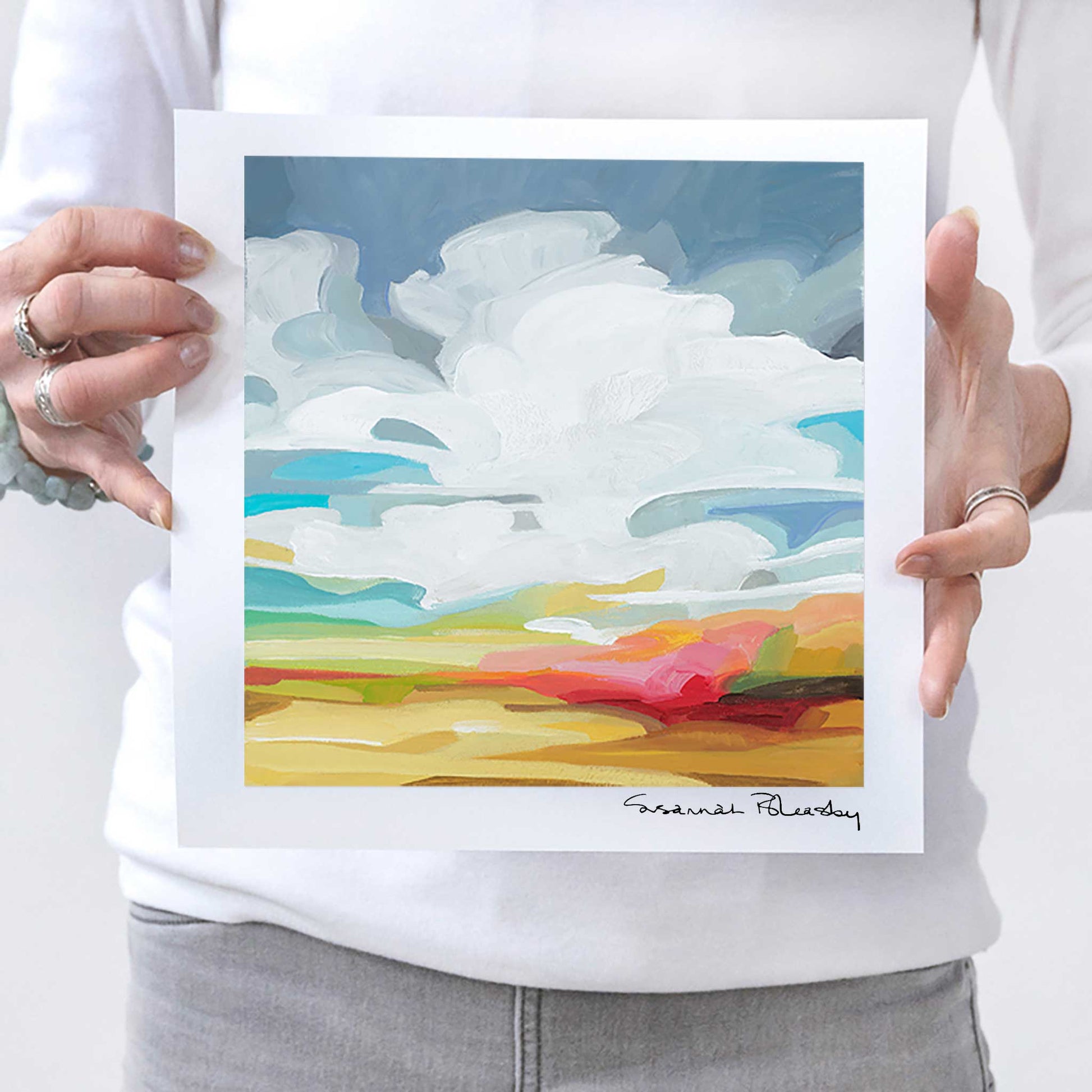 Canadian abstract artist Susannah Bleasby holding fine art print of golden sunset painting