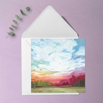 Abstract summer sky greeting card with layered sunset colours, drifting clouds, and glowing horizon reflections