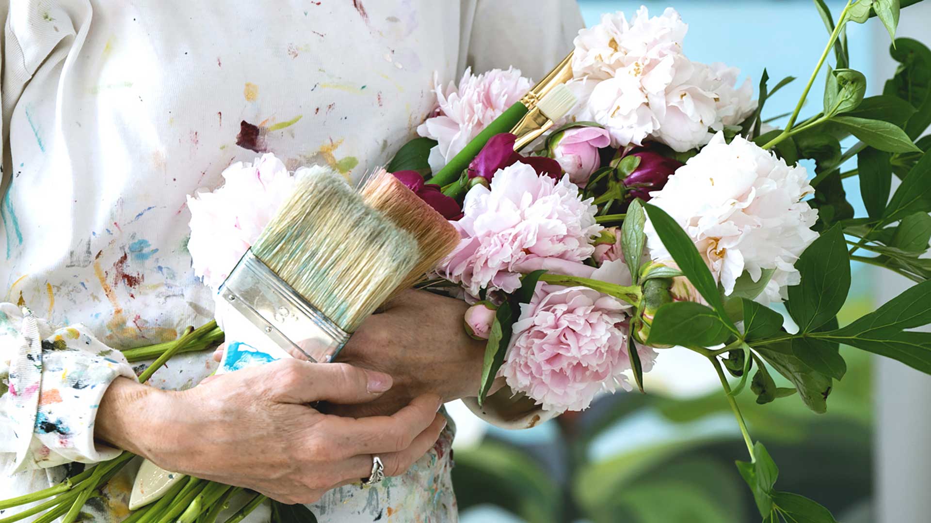artist with an armful of flowers and paint brushes
