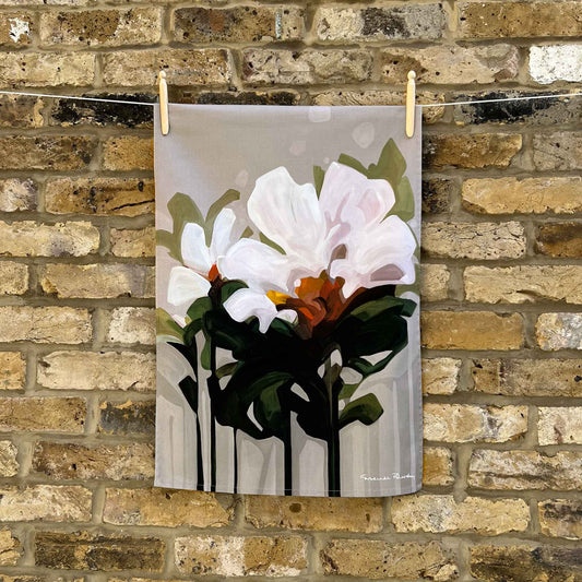 beige floral cotton tea towel hanging against a brick wall