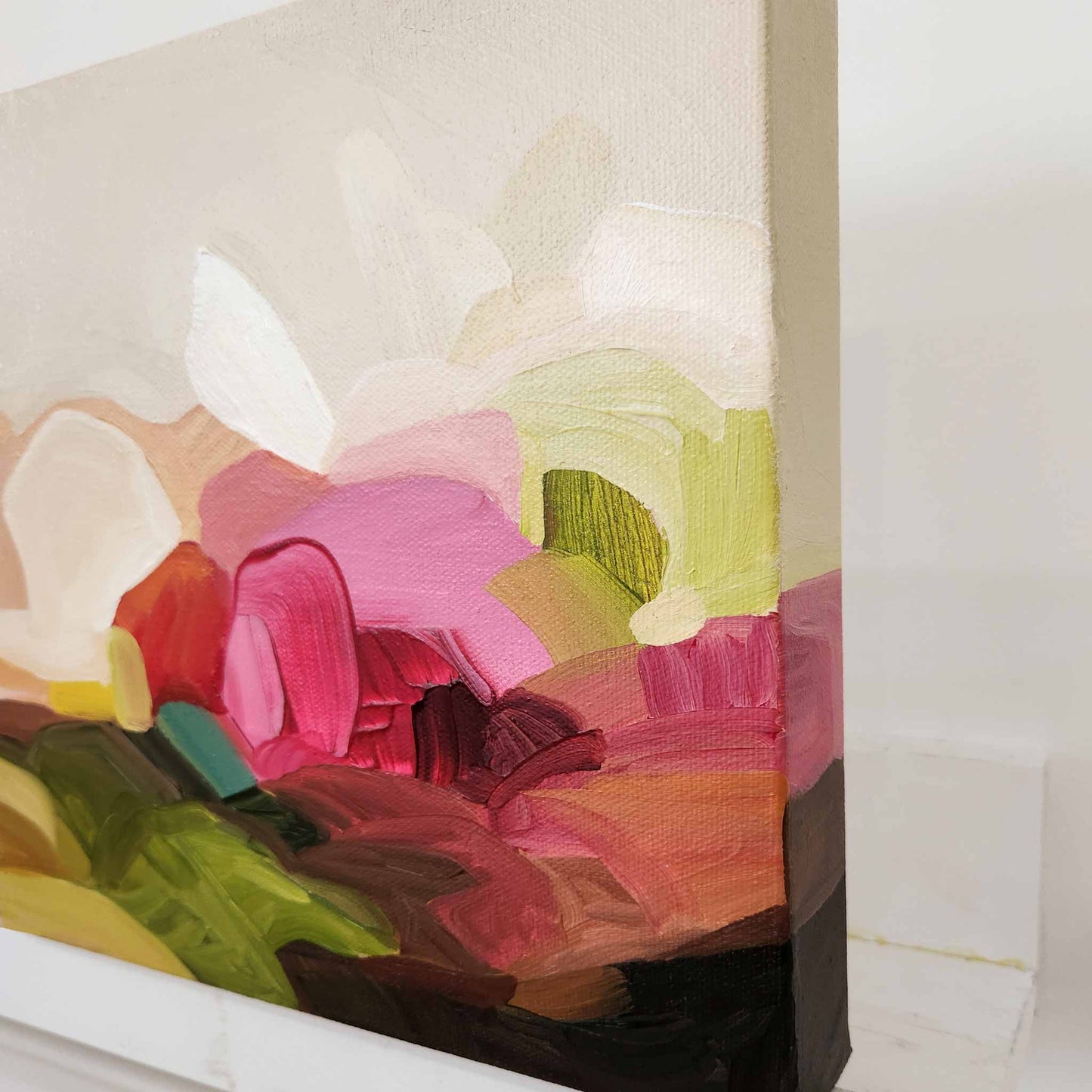 side view of small abstract painting on canvas in bright pink cream and green