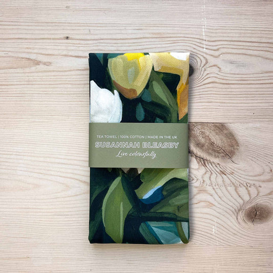 british made floral tea towel with yellow and cream flowers folded on a wooden table