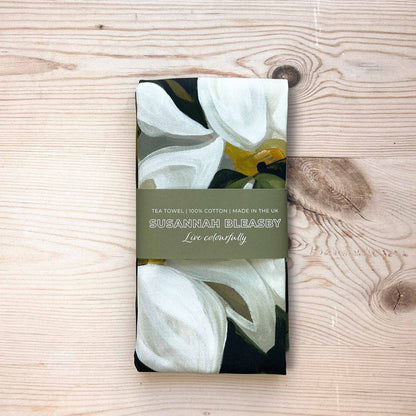 british cotton tea towel with white flowers on a dark green background folded with a bellyband