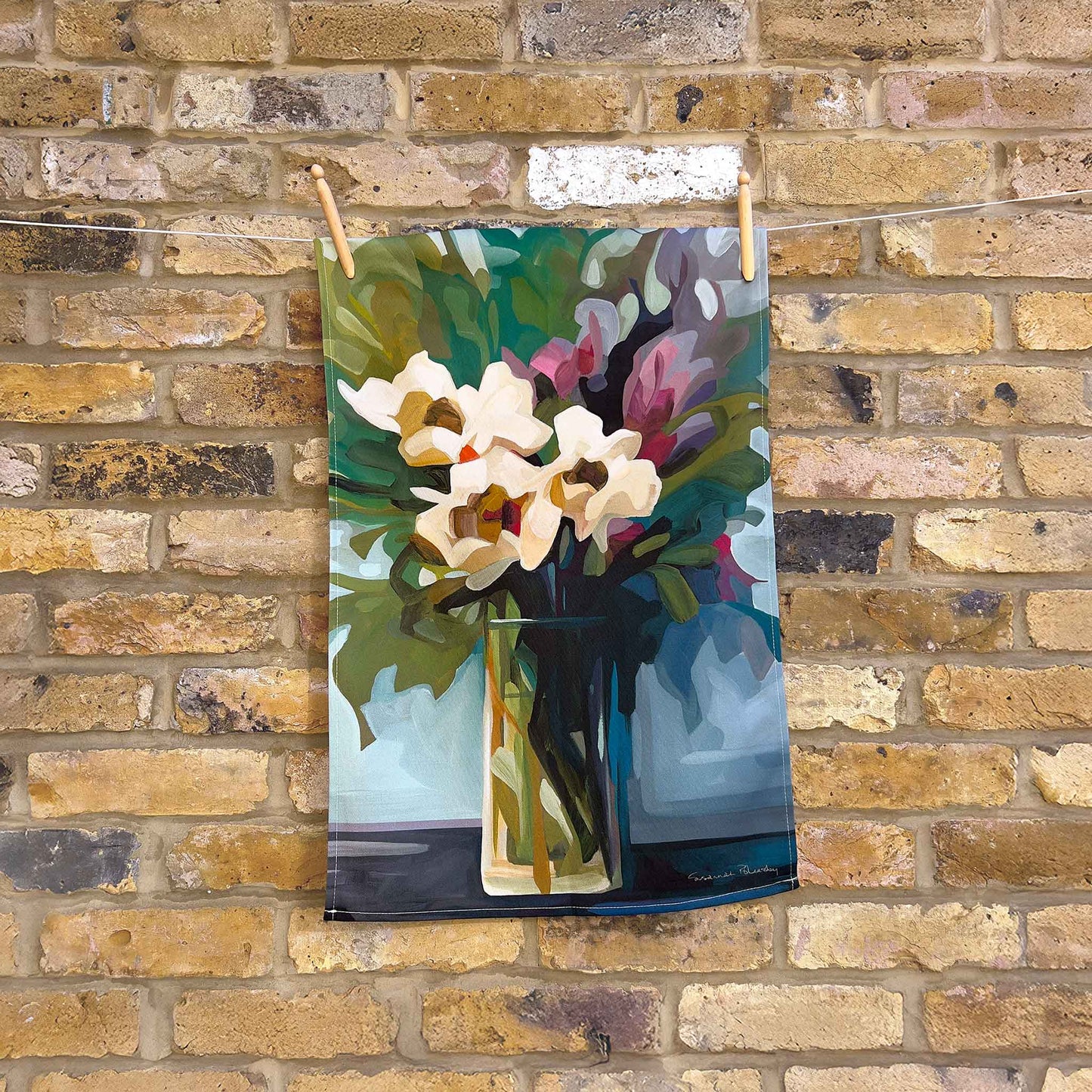 floral cotton tea towels with a painting of a bouquet of flowers hanging against a brick wall