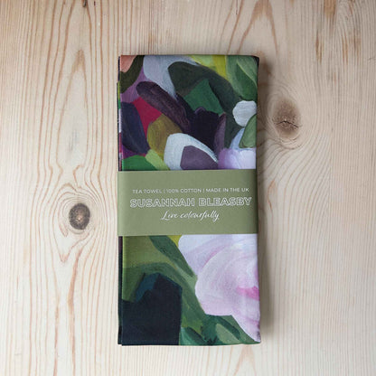 floral cotton tea towel with purple design folded with bellyband