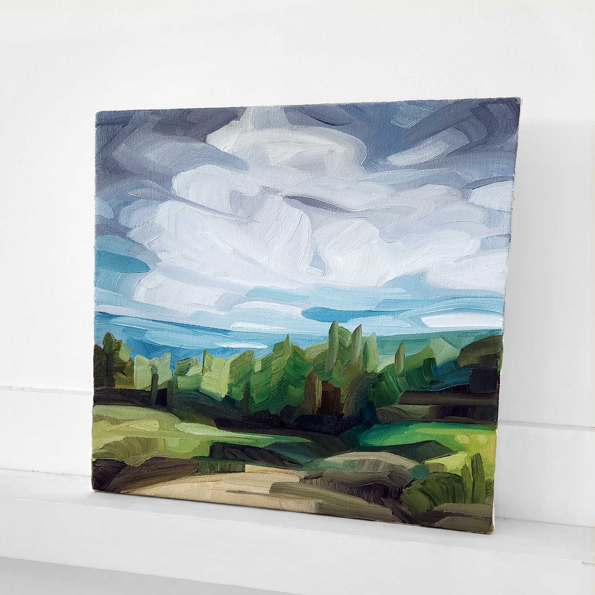 woodland landscape oil painting with lush greens a hiking trail leading to a forest and a dramatic cloud filled sky