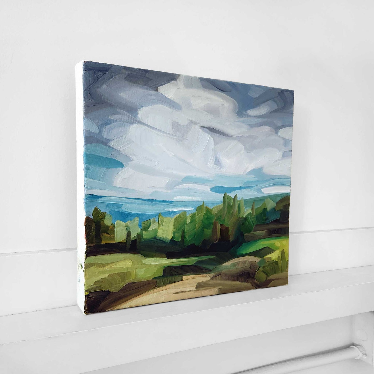 original forest landscape oil painting with a hiking trail vibrant spring greens and a blue sky with layers of sweeping coulds
