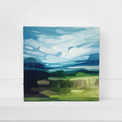 original oil painting on wood panel of a vibrant blue sky with sweeping clouds above rolling green hills