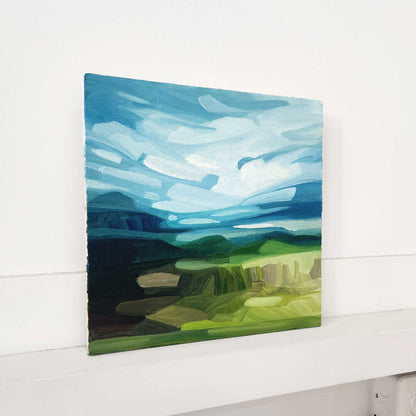 abstract landscape oil painting on wood panel with a bright blue sky and sweeping white clouds over a countryside landscape
