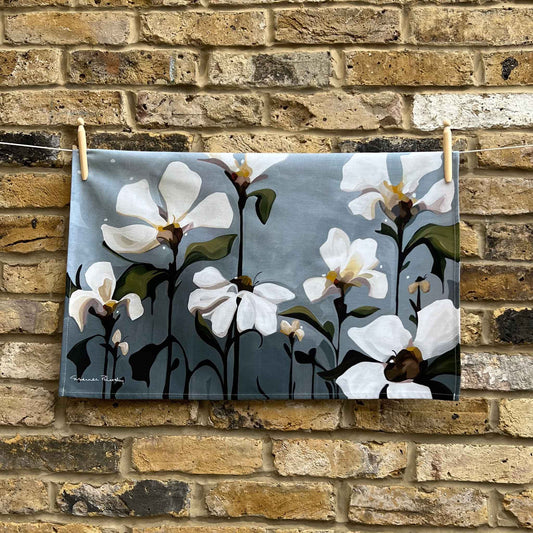 grey floral cotton tea towel hanging against a brick wall