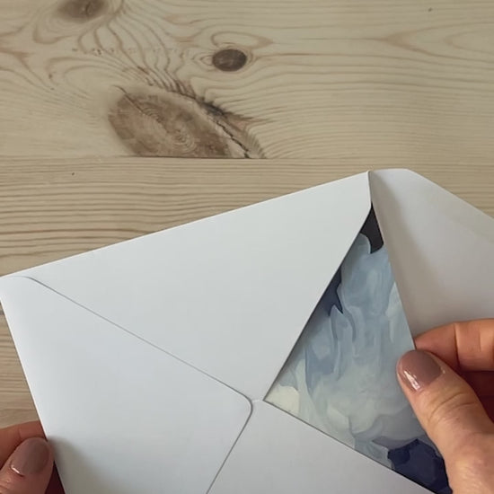 Slow motion video of colourful abstract landscape greeting card being removed from envelope featuring glowing sunrise skies and rolling green hills