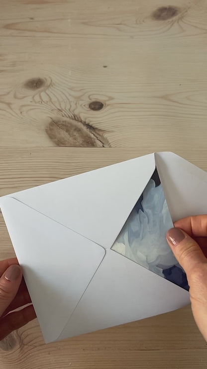 Slow motion video of colourful abstract landscape greeting card being removed from envelope featuring glowing sunrise skies and rolling green hills