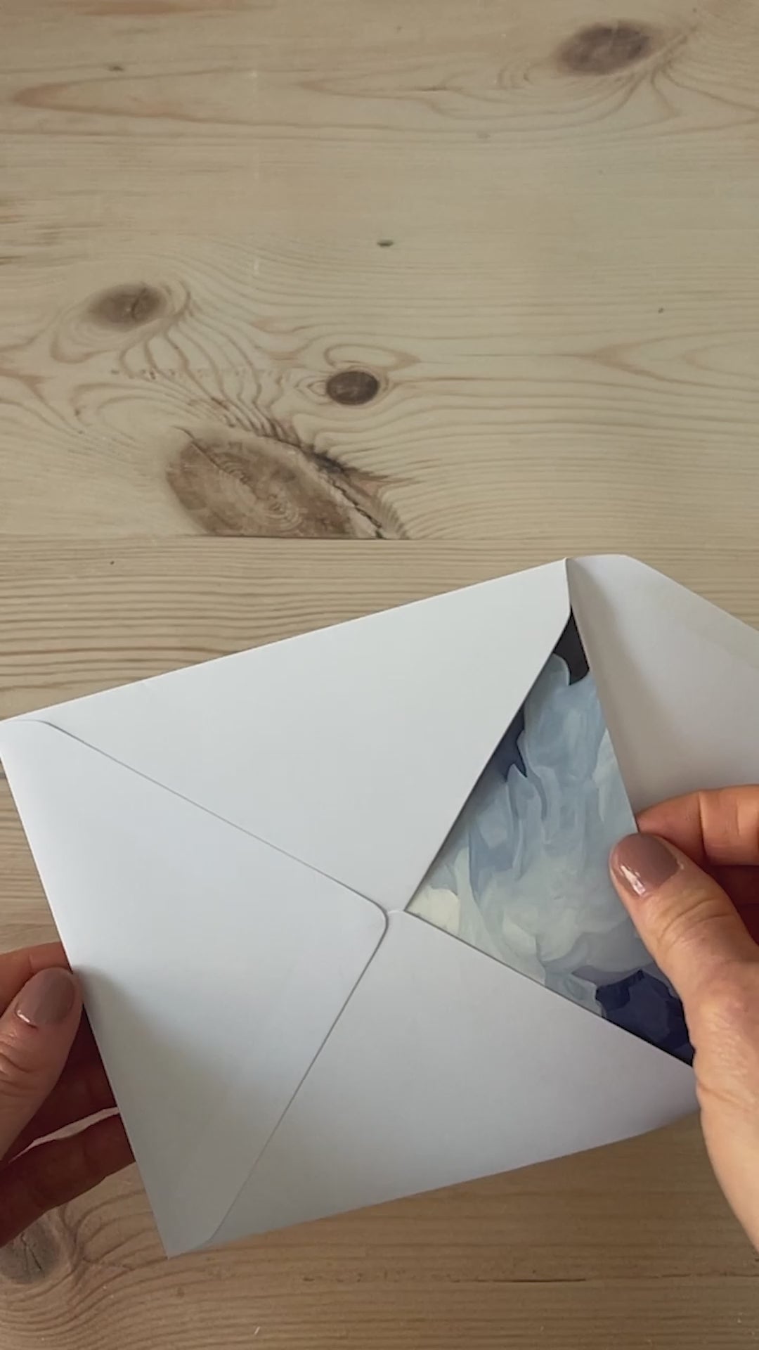 Slow motion video of colourful abstract landscape greeting card being removed from envelope featuring glowing sunrise skies and rolling green hills