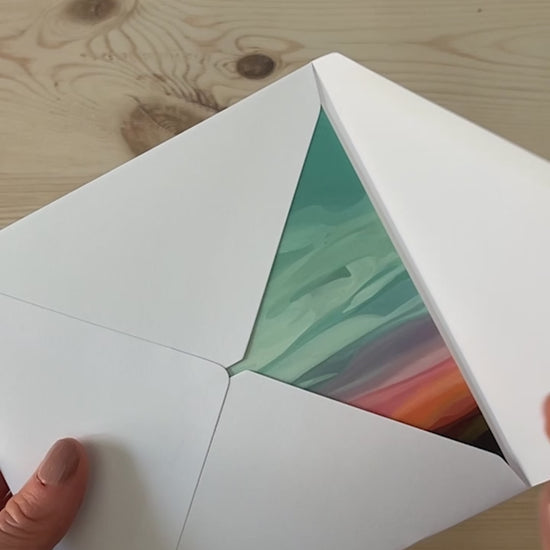 Abstract sky greeting card being opened from a white envelope with glowing sunset cloudscape artwork