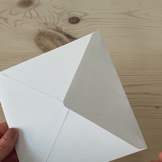 Slow motion video of contemporary abstract sky greeting card being removed from envelope featuring cobalt blue skies and glowing pink horizon light