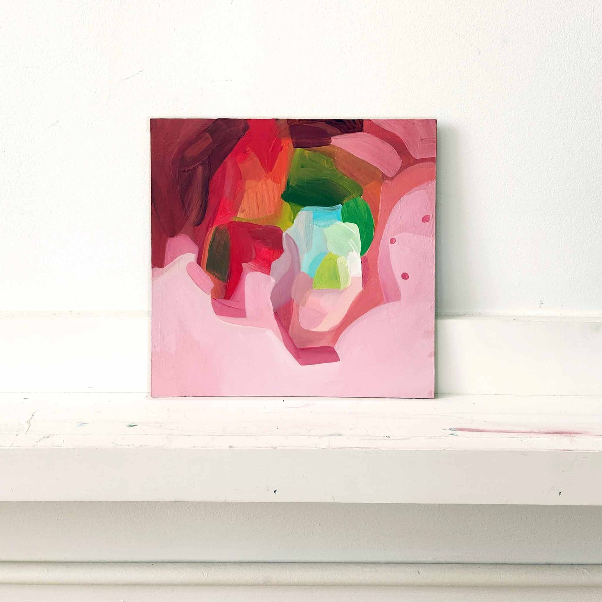 small pink and red abstract painting on ledge