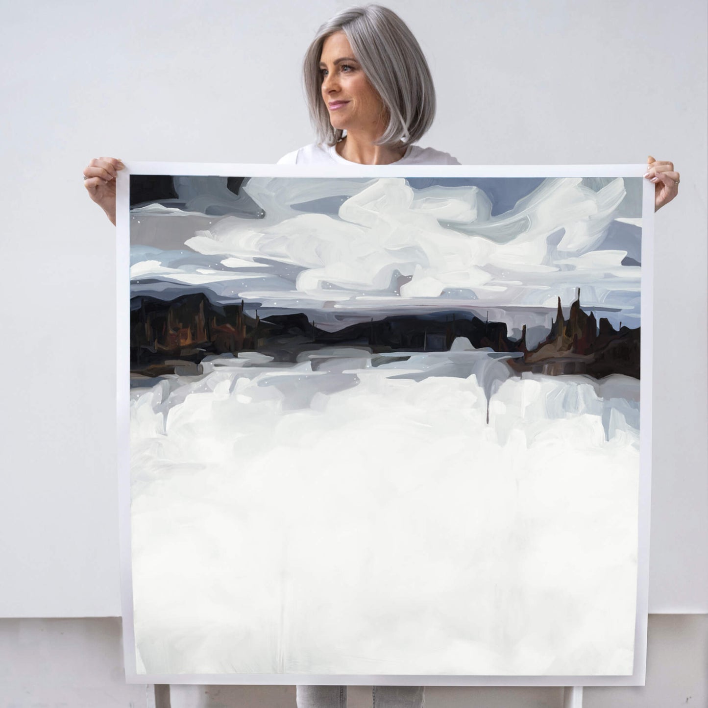 Canadian artist Susannah Bleasby holding a large fine art print of Winterland an abstract landscape painting of a winter scene
