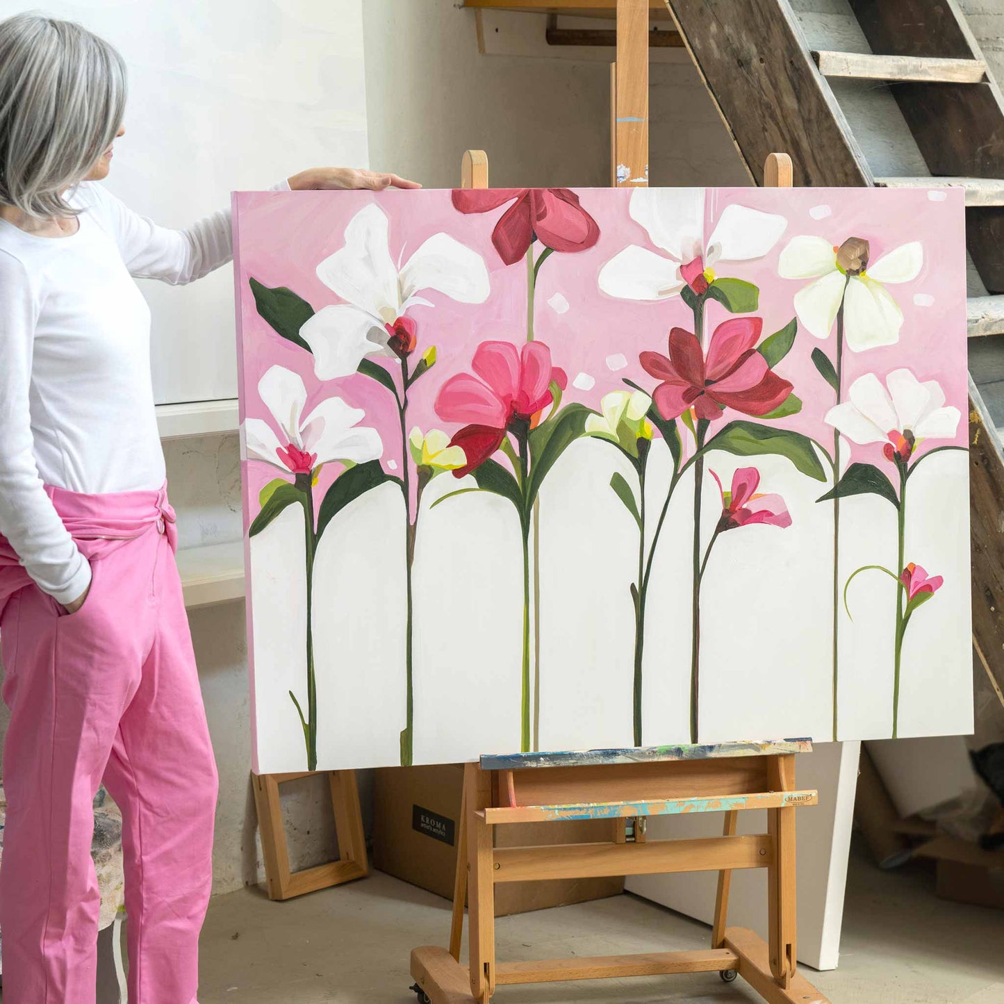 artist next to pink acrylic florwer painting on canvas in studio