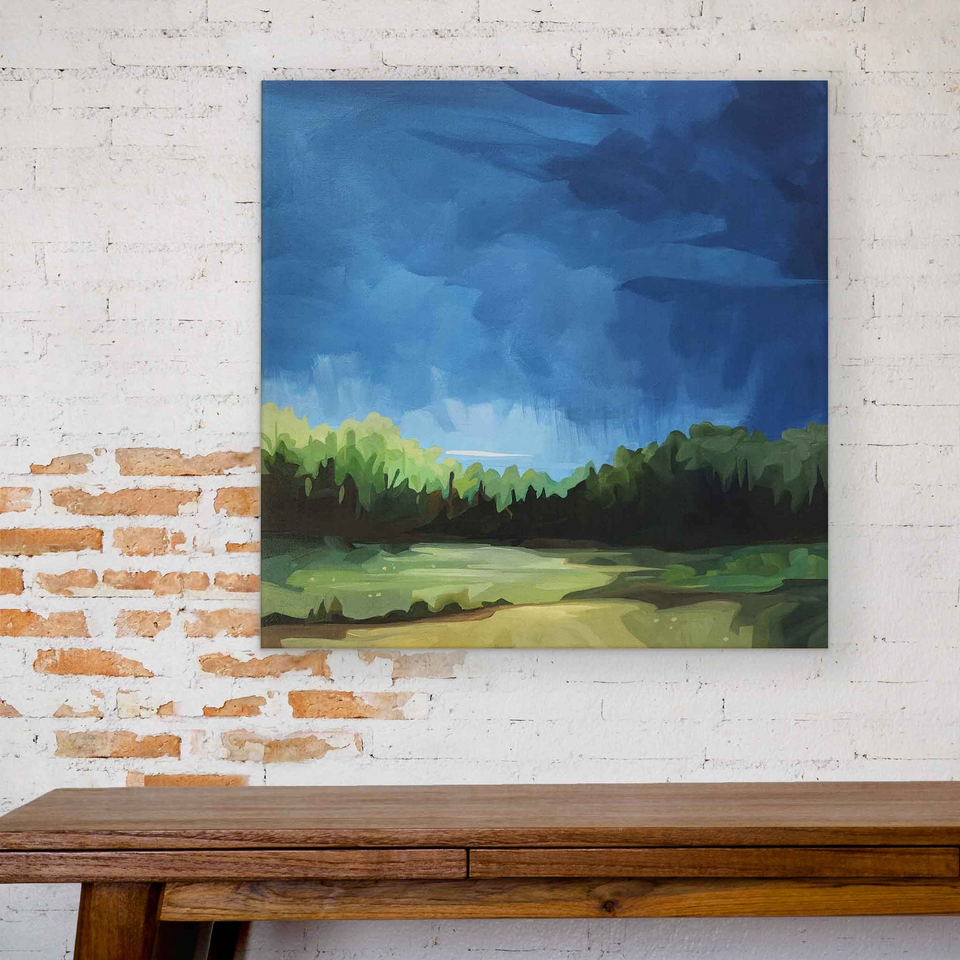 Acrylic landscape painting capturing the movement of a bright blue sky that contrasts with the fresh green of the forest landscape and fields below