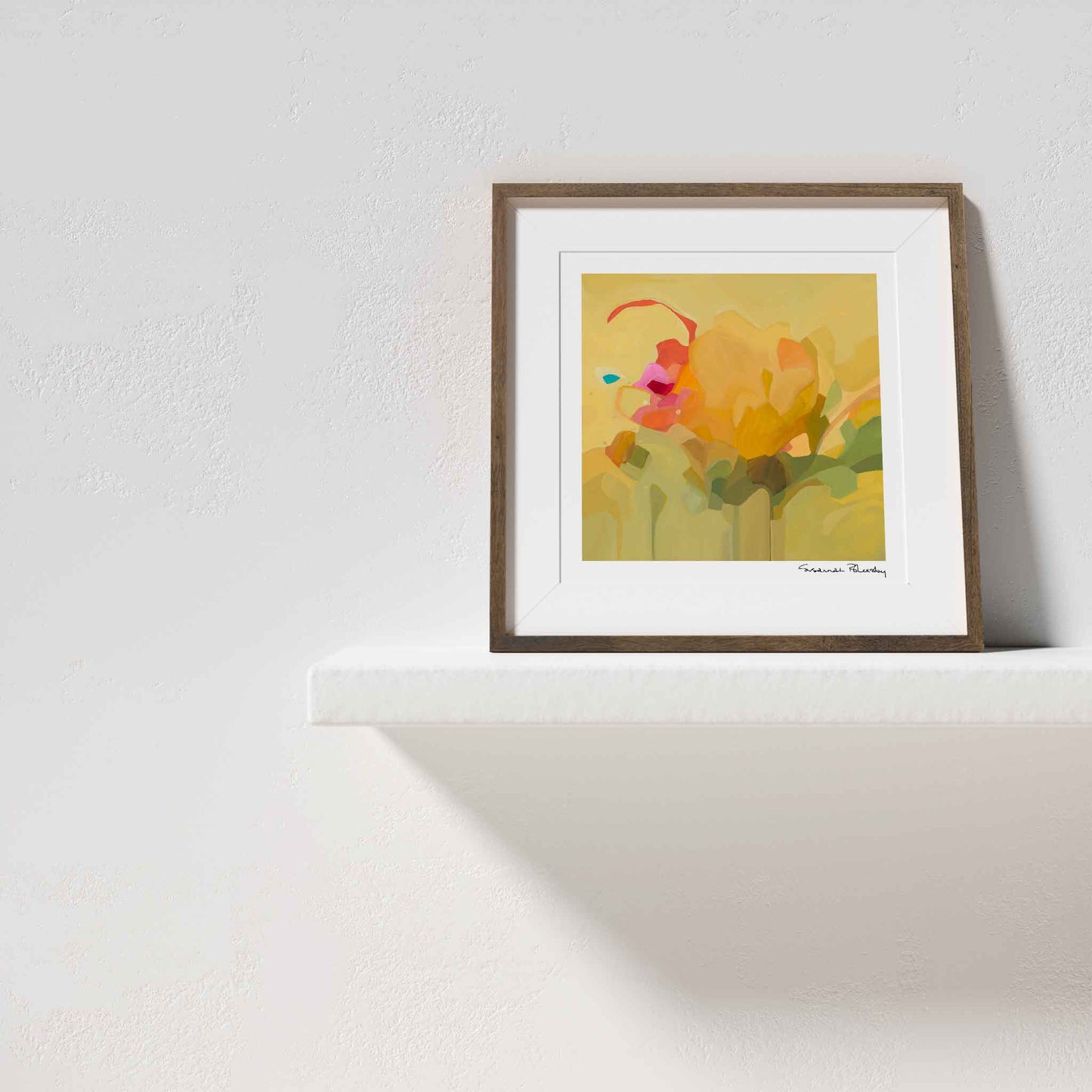 Yellow art print with abstract design framed on shelf