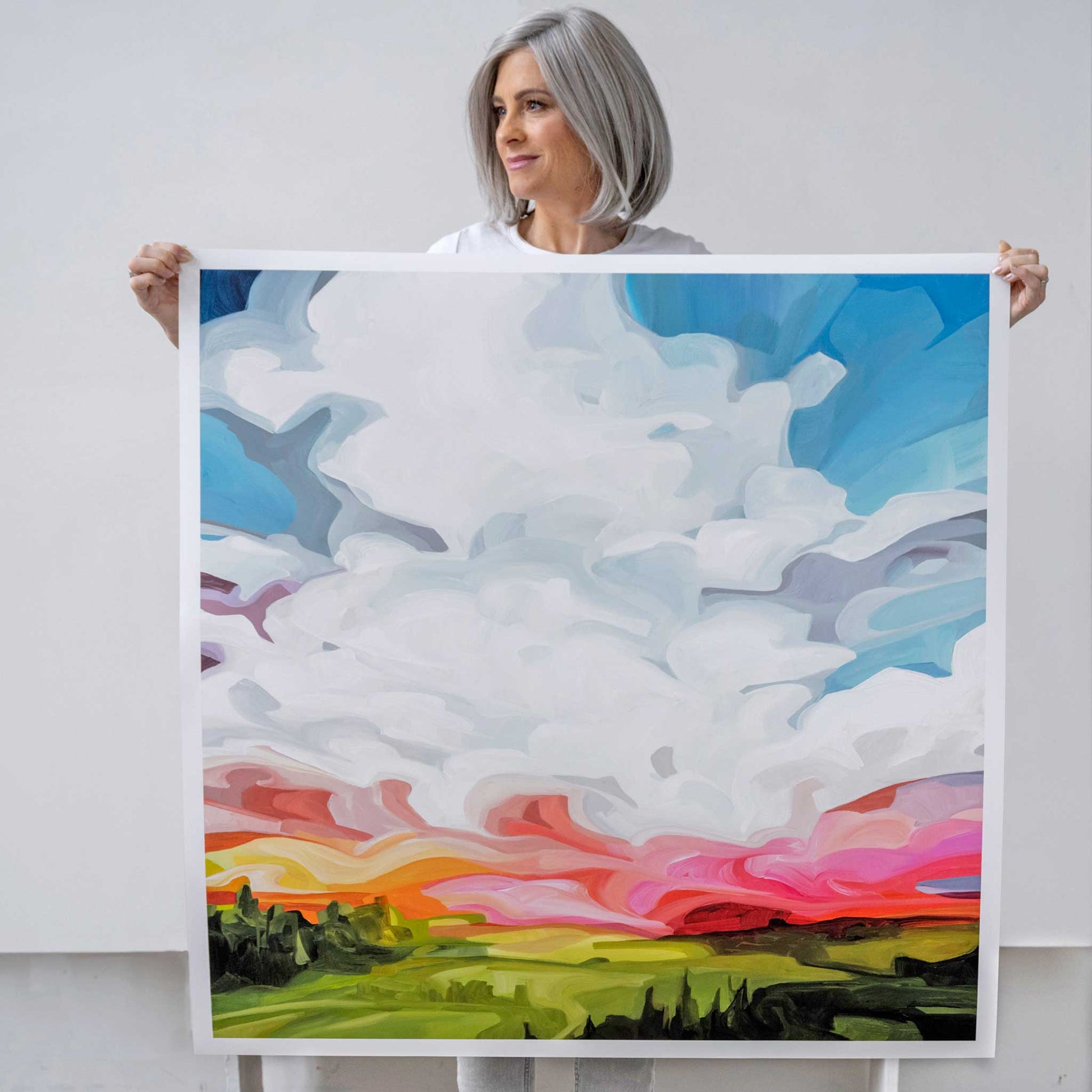 Canadian artist Susannah Bleasby holding oversized square art print of a sky sunset painting